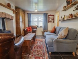 A living room with leather armchairs a blue sofa wooden coffee table and shelves with kitchen items at Briar Orchard Annex in Ammerham near Winsham