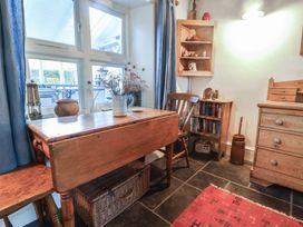 A kitchen corner with a wooden table and chairs next to a window and bookshelf at Briar Orchard Annex in Ammerham near Winsham