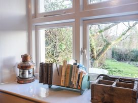 A windowsill with books in a holder a lantern and a wooden box with outdoors visible at Briar Orchard Annex Ammerham near Winsham