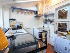 A kitchen with a sink drying rack stove kettle and shelves with mugs pots and utensils at Briar Orchard Annex Ammerham near Winsham