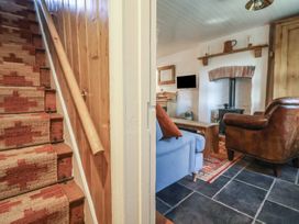 A staircase with a patterned runner leading to a living room with a blue sofa and brown leather armchair at Briar Orchard Annex in Ammerham near Winsham