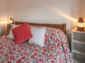 A bed with floral bedspread and pillows next to two lanterns on bedside shelves at Briar Orchard Annex Ammerham near Winsham