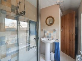 A bathroom with a glass shower enclosure a white pedestal sink a blue towel on a ring a round mirror and a wooden door at Briar Orchard Annex Ammerham near Winsham