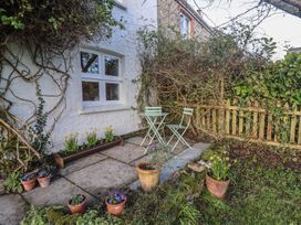 A garden patio with a small table and two chairs surrounded by flower pots and plants at Briar Orchard Annex in Ammerham near Winsham