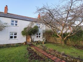 A white house with a wooden door and four windows surrounded by garden and leafless tree at Briar Orchard Annex in Ammerham near Winsham
