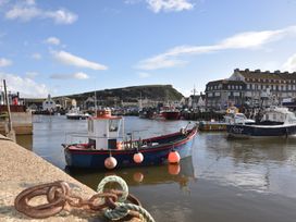 A harbor with boats docked near buildings and a hill in the background at Briar Orchard Annex in Ammerham near Winsham