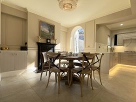 A dining area with a round wooden table and chairs near a black fireplace and an arched door opening to the outside at Ivy House in Conwy