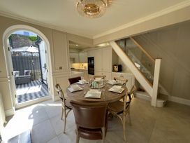 A dining area with a round wooden table set with plates and glasses next to a kitchen and stairs at Ivy House in Conwy
