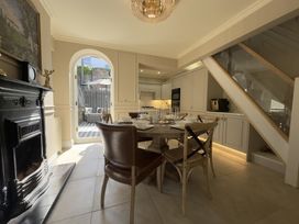 A kitchen and dining area with a round wooden table set for four and an open door to a patio at Ivy House in Conwy