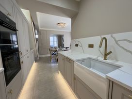 A kitchen with cabinets a sink and a dining area beyond at Ivy House in Conwy