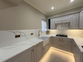 A kitchen with grey cabinets white marble countertops built in stove and under cabinet lighting at Ivy House in Conwy