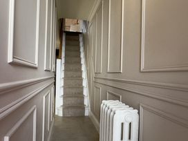 A hallway with a carpeted staircase and a white radiator on the right wall at Ivy House in Conwy