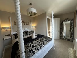 A bedroom with a four-poster bed a large decorative mirror and a light fixture at Ivy House in Conwy