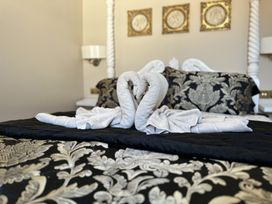 A bedroom with two towel swans on a bed with black and gold patterned bedding at Ivy House in Conwy