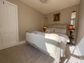A bedroom with a bed featuring a carved wooden frame two side tables with lamps two mirrors and a painting above the bed at Ivy House in Conwy
