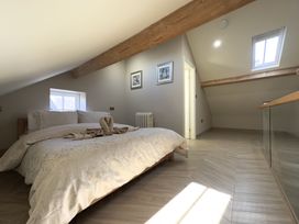 A bedroom with a bed under a sloped ceiling with wooden beams and two framed pictures on the wall at Ivy House in Conwy
