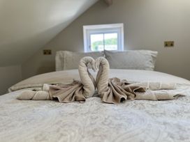 A bed with two towel swans forming a heart shape at Ivy House in Conwy