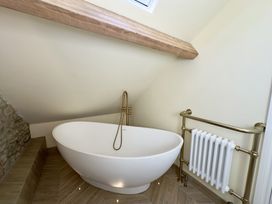 A bathroom with a freestanding bathtub under a sloped ceiling and a radiator at Ivy House in Conwy