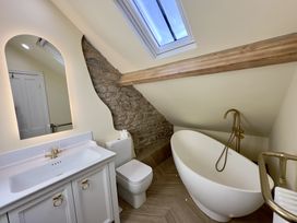 A bathroom with a freestanding bathtub a toilet a sink with a mirror and a skylight at Ivy House in Conwy
