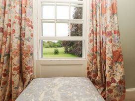 A window with floral curtains overlooking a green field at Westward Park near Wigton