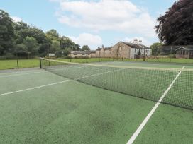 A tennis court with a net and a building in the background at Westward Park near Wigton