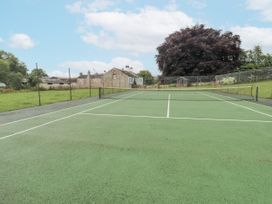 A tennis court with a net and buildings in the background at Westward Park near Wigton