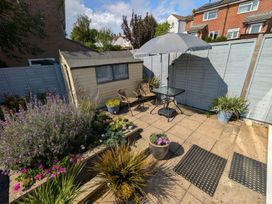 A garden with a table under an umbrella and a shed at Seahills in Lyme Regis