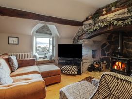 A living room with a brown sofa a patterned chair a fireplace and a window with a view at Top Cottage in Barmouth