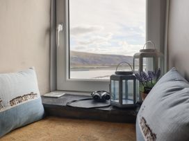 A window seat with cushions lanterns binoculars and a small plant at Top Cottage in Barmouth