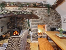A living room with a fireplace a wood stove patterned armchairs a wooden dining table and an orange bench at Top Cottage in Barmouth