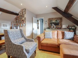 A living room with a patterned armchair and a leather sofa with pillows at Top Cottage in Barmouth