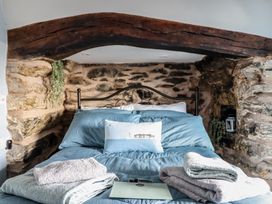 A bed with blue bedding and folded towels in a stone walled bedroom at Top Cottage in Barmouth