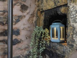 A stone wall with a small alcove holding a blue lantern and a trailing green plant at Top Cottage in Barmouth