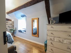 A bedroom with wooden beams a window seat a mirror and a chest of drawers with a television at Top Cottage in Barmouth