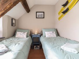 A bedroom with two single beds a blue bedside table and wooden beams at Top Cottage in Barmouth
