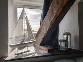 A window sill with a decorative model sailboat and two lanterns beside a wooden beam at Top Cottage in Barmouth