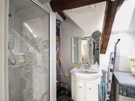 A bathroom with a sink and mirror wooden beams a washing machine and a shower at Top Cottage in Barmouth