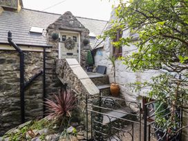 The front entrance of a stone cottage with stairs leading to a door surrounded by plants and a metal gate at Top Cottage in Barmouth