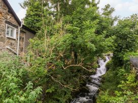 A stone house with trees and a waterfall at Waterfall Retreat in Blaenau Ffestiniog