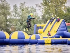 An inflatable water park with children and adults enjoying activities at Ripples & Reeds - Billing Aquadrome