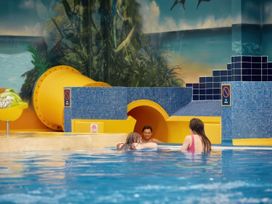 A swimming pool with a water slide and children playing at Ripples & Reeds - Billing Aquadrome