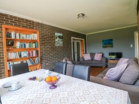 A living room with a table, sofa, bookshelves, and television at Beech Lodge, Foulksmills, County Wexford