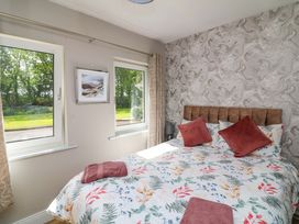 A bedroom with a bed and windows at Beech Lodge Foulksmills, County Wexford