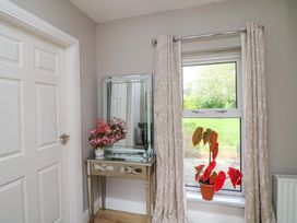 A hallway with a mirror and a plant by the window at Beech Lodge, Foulksmills, County Wexford