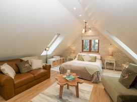 A bedroom with a bed two sofas a wooden coffee table and wallpaper with floral patterns at Pheasants Rise Apartment in Ross-On-Wye