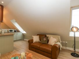 A small open plan living area with a brown sofa and kitchen appliances at Pheasants Rise Apartment in Ross-On-Wye