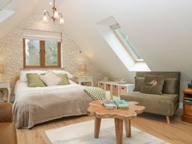 A bedroom with a bed, green sofa, wooden coffee table, and sloped ceiling with skylight at Pheasants Rise Apartment in Ross-On-Wye