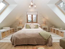 A bedroom with a bed in the center, nightstands with lamps on each side, storage baskets below skylight windows and a small window on the back wall at Pheasants Rise Apartment in Ross-On-Wye