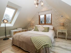 A bedroom with a double bed two bedside tables with lamps a skylight window and a window with floral wallpaper at Pheasants Rise Apartment in Ross-On-Wye