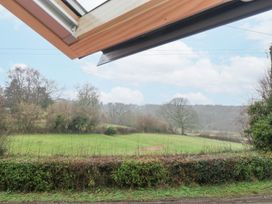 A green field with bushes and trees viewed through an open window at Pheasants Rise Apartment in Ross-On-Wye